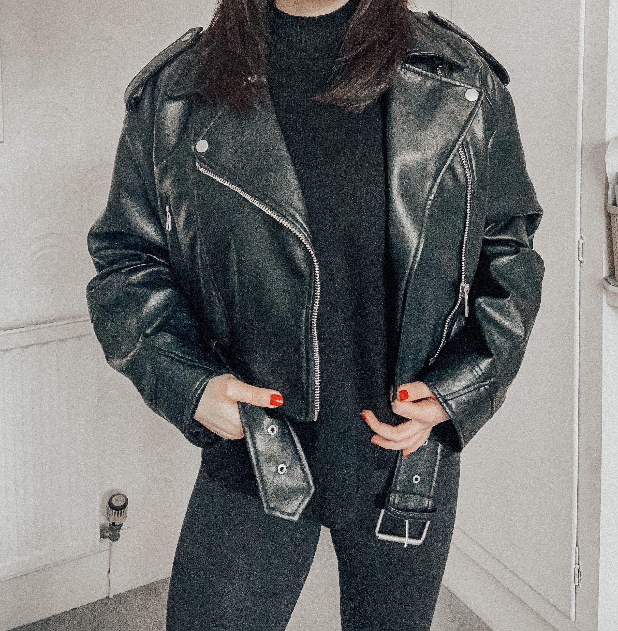 A woman wearing a black leather jacket and black jumper.