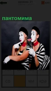 двое людей изображают пантомиму с масками на лицах