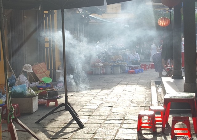 A street food vendor grilling some meat skewers.