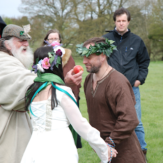 Handfasted couple about to bite an apple in a fertility rite, held by the Archdruid of Avebury, Terry Dobney