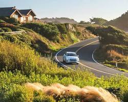 An electric car drives along a scenic highway in California.