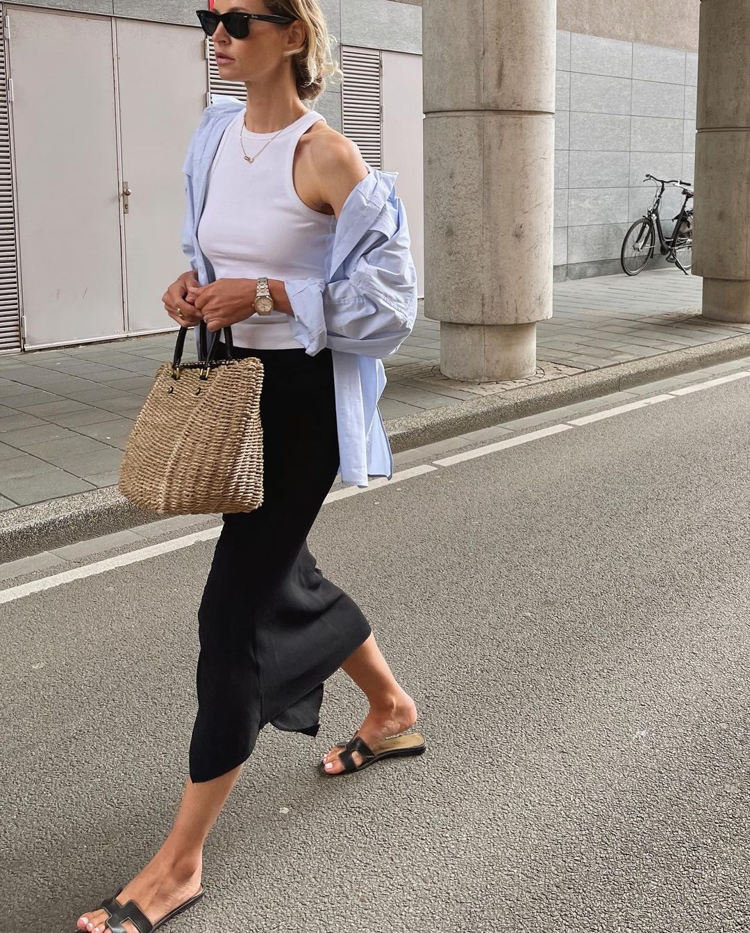 Easy Stylish Summer Outfit Inspiration — Anouk Yve in a blue button-down shirt, white racerback tank top, black midi slip skirt, Hermes flat slide sandals