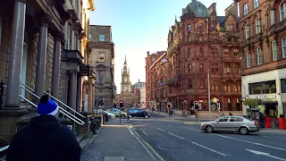Looking down the a street in Glasgow. Red brick buildings and shops line the street.
