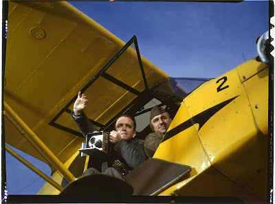 Man holds a camera in a yellow airplane