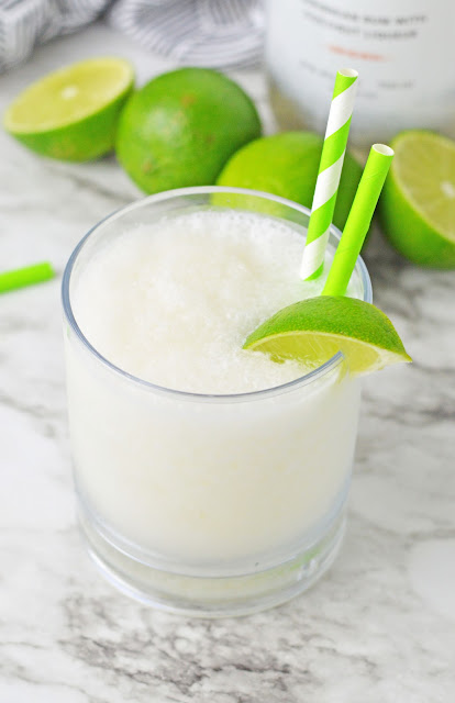 slushie in a clear glass with lime garnish.