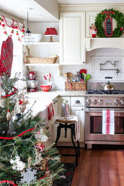 Farmhouse style kitchen with red accents and boxwood wreaths as Christmas decor