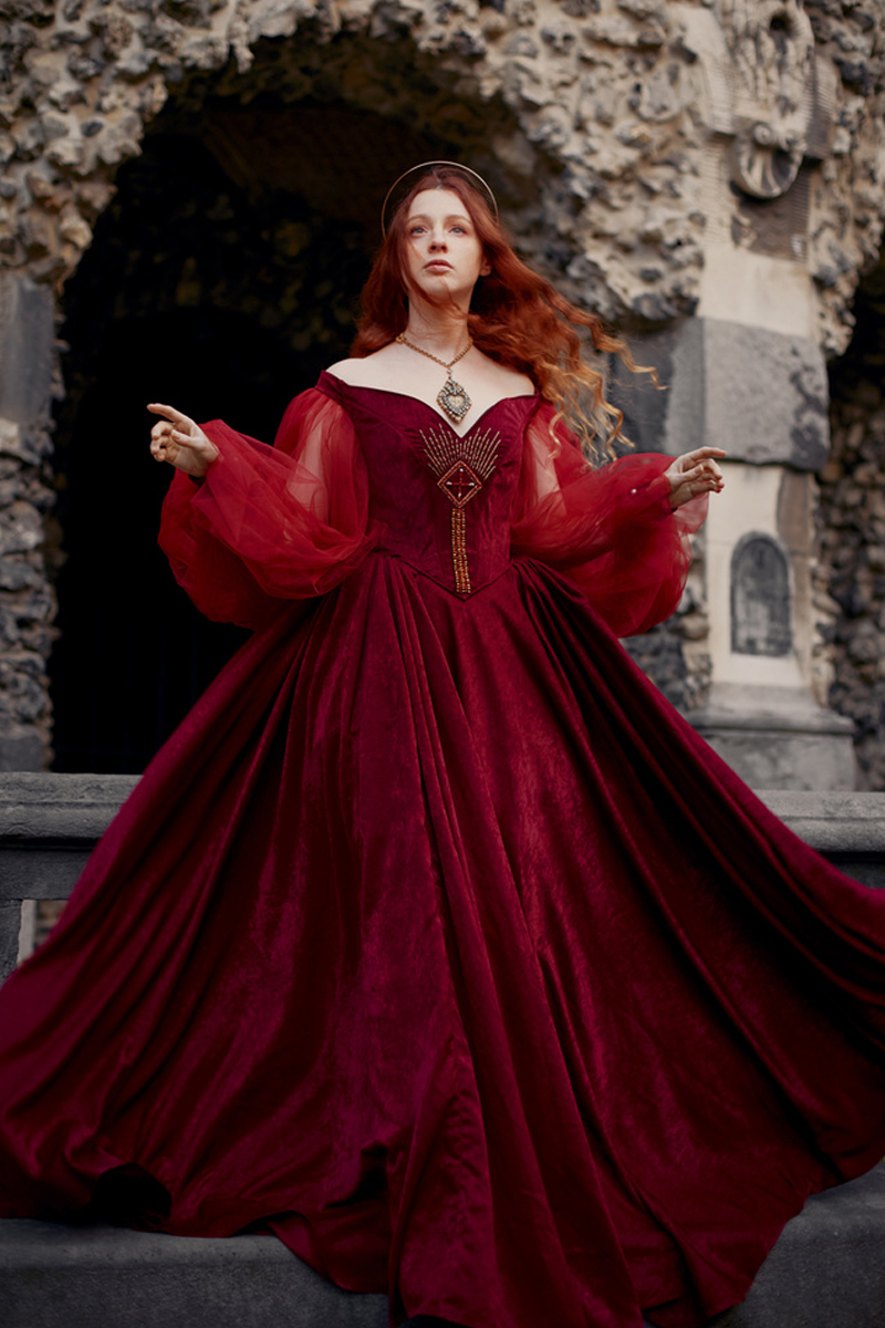portrait of a young woman in a red medieval dress and loose ginger hair