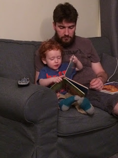 Little boy, sitting with his Daddy, reading the book