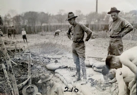 A black and white photograph of two men in uniform overseeing a trench.