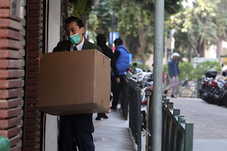 Man in green mask delivering large box