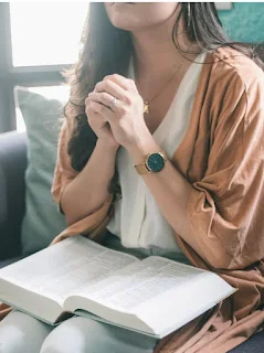 A lady praying with bible on her thighs