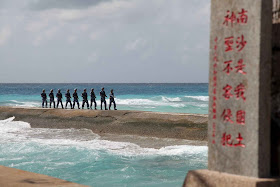 Fevereiro 2016: soldados chineses nas ilhas Spratly (Nansha para a China) . A placa diz: "Nansha é nossa terra nacional, sagrada e inviolável".