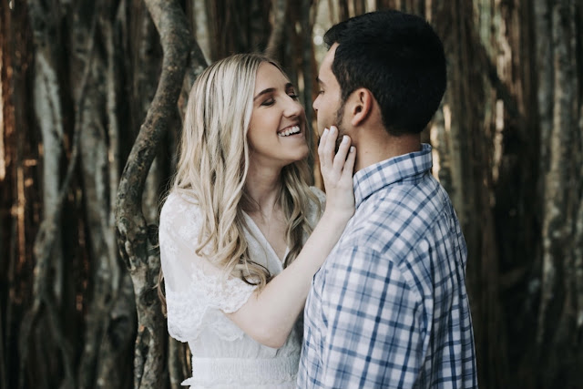 couple smiling in front of trees