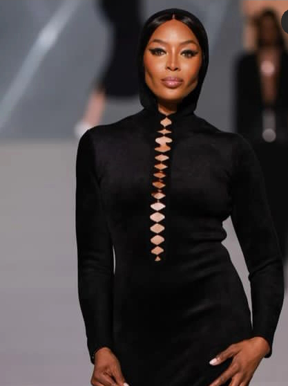 Naomi Campbell Flaunts Her Curves In A Black Long Sleeve Neck Dress At A Fashion Event