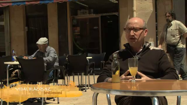 Fotograma del documental on se'm veu passant per darrera d'un entrevistat a una terrassa de la Plaça de la Font