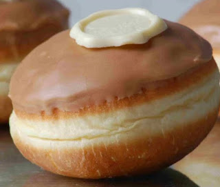 Close-up of a doughnut. It's got caramel coloured icing, with a white chocolate button on top.