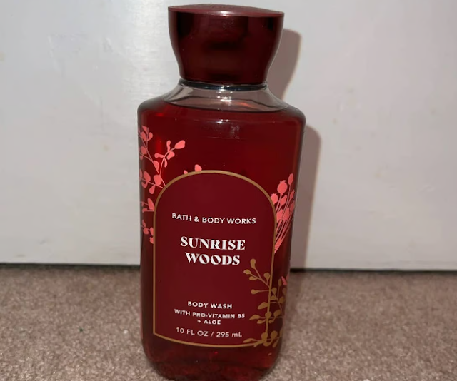 Bath & Body Works’ Sunrise Woods Body Wash maroon label bottle with peach pink & gold flowers, leaves & branches & white font