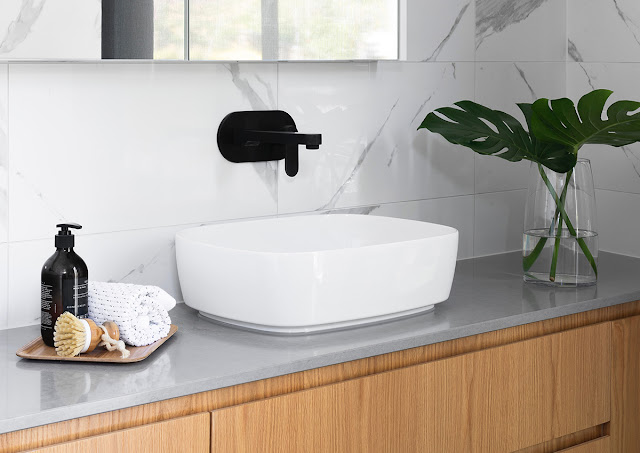 A mid-century modern bathroom vanity is softened with tropical foliage.