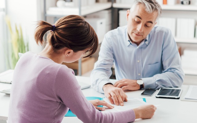 Employer and employee conversing over paperwork