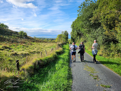 Three pilgrims walking in Irish countryside.