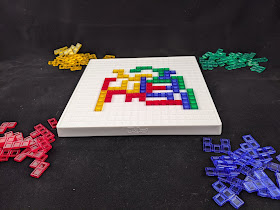 A game in progress. A number of pieces in the various colours have been placed on the board, while the remaining pieces are piled at each corner.