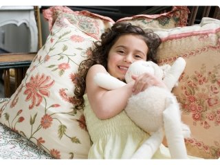 A little girl happily hugging her white lamb soft toy