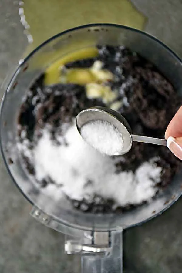 Adding sugar and butter to crushed oreos in food processor for Raspberry White Chocolate Cheesecake crust recipe