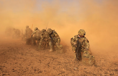 Royal Marines with 40 Commando are engulfed in dust after disembarking from a helicopter and watching it lift off again on the 1st of January 2013