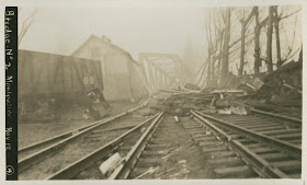 A black and white photograph of a damaged railroad, covered in debris.