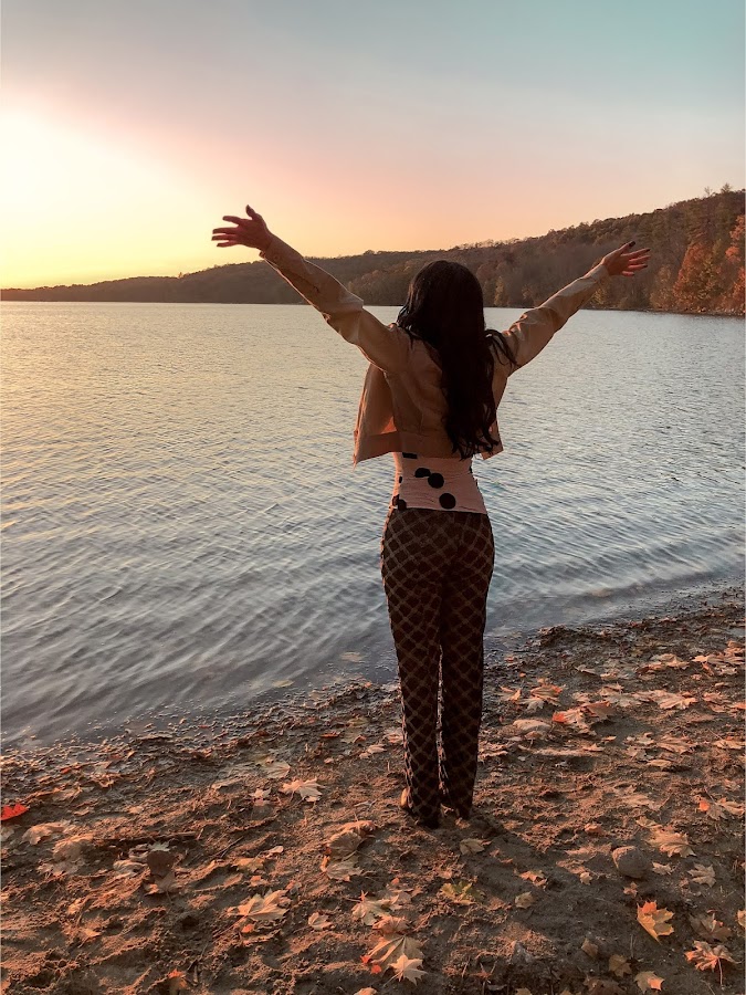 Arms open , high up, celebrating life, enjoying nature, Lina Mayorga Crop jacket sustainable, beige jacket, neutral tones, Versace logo pants, brown beige medusa logo, Jacquemus polka dot top strapple top, beige top with black dots, trees and leaves and a lake in the background, fall mood, North Salem, NY 2020