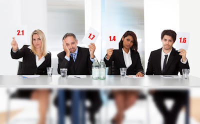 4 businesspeople sit behind a table and hold up low rating cards