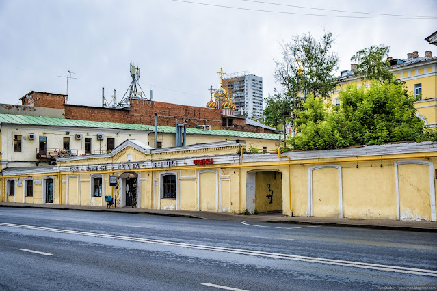 Желтое одноэтажное здание с арочными воротами