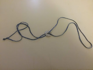 A 1 inch pewter disk on a 40 inch blue hand-braided cord.