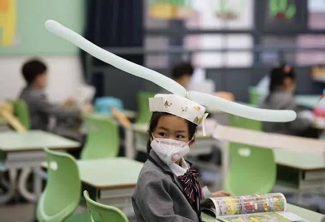 Students wear social distancing headgears to class as schools resume in China