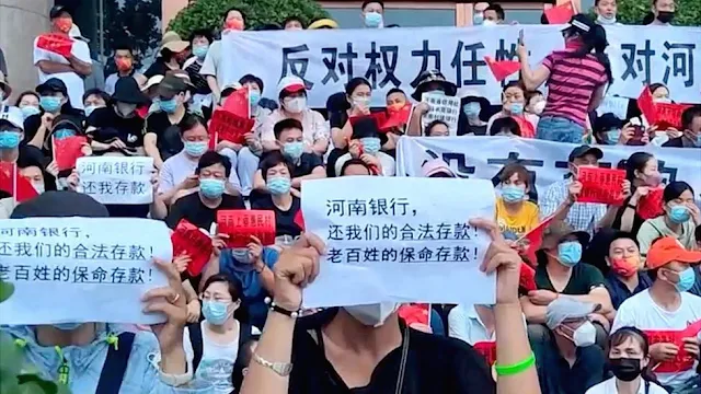 Cover Image Attribute: Outside of a branch of the People's Bank of China in Zhengzhou, Henan province, on July 10, 2022, demonstrators carried banners with the inscription "Henan banks, give me my money back." / Source: BBC