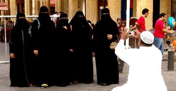 An Arabian person is taking photographs of women in veils