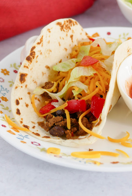 taco on a white plate with a bowl of salsa on the side.