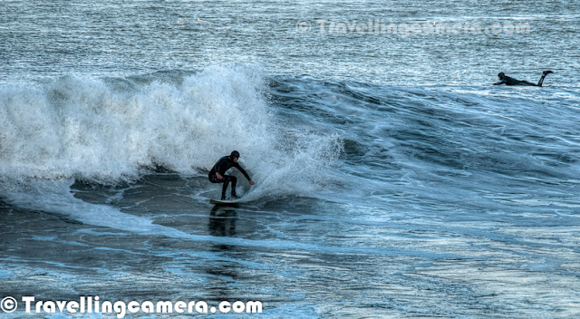 Photo Walk around San Francisco was one of the highlight of my recent trip to US and our last spot during the PHOTO WALK was Surfing point under Golden Bridge. This Photo Journey shares some of the moments captured under Golden Bridge of San Francisco. Surfing is a surface water sport in which the wave rider, 'surfer', rides on the forward face of a wave. Waves suitable for surfing are found primarily in the ocean, but can be found in some lakes, in rivers in the form of a standing wave. Surfing can also be done in artificial water sources such as wave pools and boat wakes. The term 'surfing' refers to the act of riding a wave and not the form in which the wave is ridden After having lunch at De Young Museum, we moved to the bottom of Golden Bridge where lot of surfers were getting ready for surfing in Pacific Ocean. They were carrying surfing boards in their cars and changing the cloths to gear up for a great adventure in water. Most of the these photographs are cropped versions, as they were surfing at a significant distance from shoreline.  This is first time that I saw people doing surfing in front of me and even when chilled wind was blowing all around the San Francisco town. It was a cloudy day and most of us were wearing multi-layered cloths. After coming back from this point, I realized that I should have made a video of these folks surfing in the ocean as action is not well captured in these photographs. It's really amazing to see surfers playing so well with high waves in ocean.Surfing can be done on various equipments including surfboards, longboards, Stand Up Paddle boards (SUP's), bodyboards, wave skis, skimboards, kneeboards, surf mats and macca's trays. Surfers of different age groups were there at Golden Bridge to enjoy the day... After mild rains in the morning, sun was out.Three major subdivisions within sitting-up surfing are longboarding, shortboarding, and stand up paddle surfing (SUP), reflecting differences in board design, including surfboard length, riding style and the kind of wave that is ridden.Surfers represent a diverse culture based on riding the waves. Some people practice surfing as a recreational activity while others make it the central focus of their lives. Within the United States, surfing culture is most dominant in Hawaii and California because these two states offer the best surfing conditions. Some historical markers of the culture included the woodie, the station wagon used to carry surfers' boards, as well as boardshorts, the long swim shorts typically worn while surfing.Several of San Francisco's parks and nearly all of its beaches form part of the regional Golden Gate National Recreation Area, one of the most visited units of the National Park system in the United States with over 13 million visitors a year. Among the GGNRA's attractions within the city are Ocean Beach, which runs along the Pacific Ocean shoreline and is frequented by a vibrant surfing community.