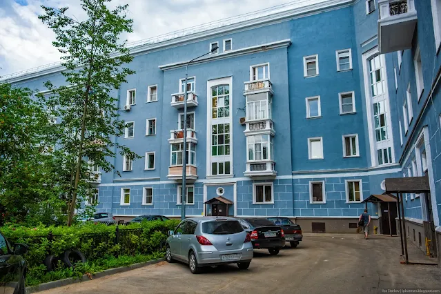 Машины припаркованы у синего многоквартирного здания