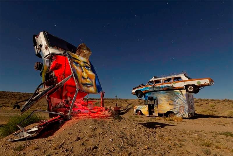 At the edge of Goldfield, a small town in the middle of Nevada, multiple cars, buses, vans, and limos are buried vertically in the desert as if they are growing out of the ground.