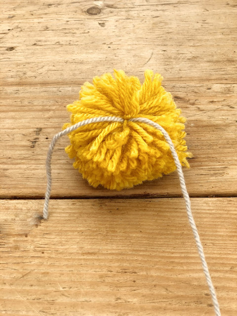 DIY tutorial to make a wool pom pom garland on belly basket for £10. Summer interior trend and storage solution you can craft and create yourself on a tight budget