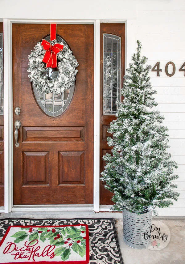 front door with flocked wreath and tree