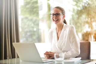 A woman smiling at her computer | collection agency Kentwood