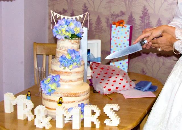 a wedding cake about to be cut by a bride and groom
