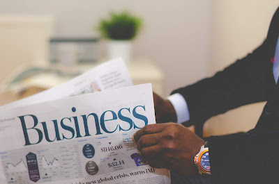 black man's hands holding a Business newspaper