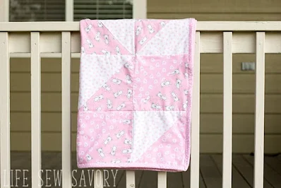 pink baby quilt hung over a railing