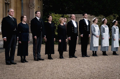 Jim Carter, Phyllis Logan, Brendan Coyle, Raquel Cassidy, Joanne Froggatt, Kevin Doyle, and Michael Fox stand to greet the queen in a movie still for the 2019 drama film Downton Abbey