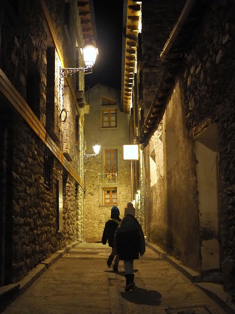 Vista nocturna de un callejón en un pueblo con dos niños andando