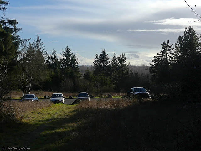 parking lot with four cars and two picnic tables