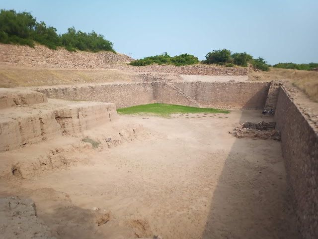 Empty reservoir cut into ground with stairs leading into it at Dholavira